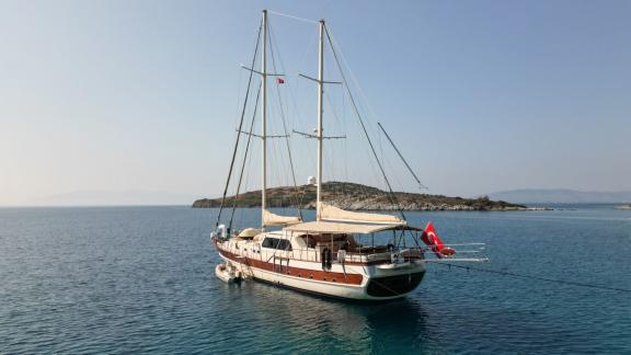 Gulet yacht flying the Turkish flag anchored in calm waters off the coast.