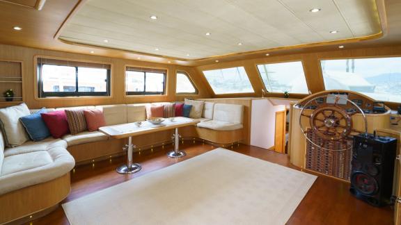 Elegant saloon of the gulet Happy Hours in Bodrum with comfortable seating area and steering wheel.