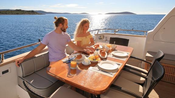 Image of a couple having breakfast outdoors on the deck of the Hope I yacht.