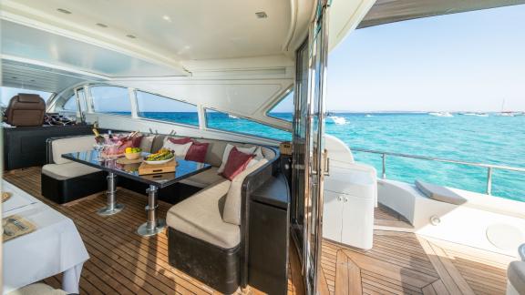 The motor yacht Aya One features a large dining table and a comfortable seating arrangement on the open deck.