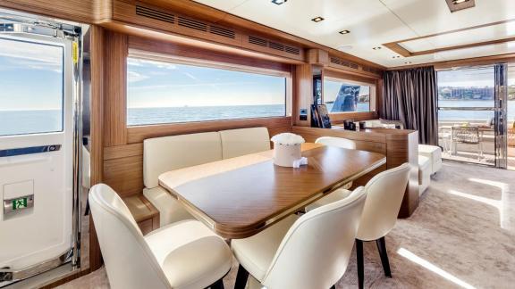 Spacious dining table and white leather chairs with sea view on Sirena 64.