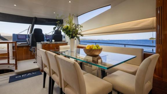 Inside the Sunseeker 75 near Split is a glass table with cozy chairs and wide sea views through the window.