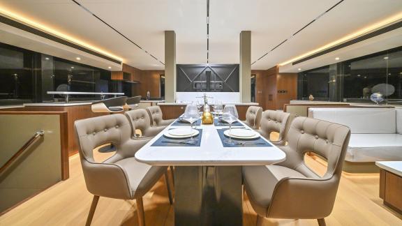Evita power catamaran features a long dining table, elegant chairs and an open galley in the saloon.