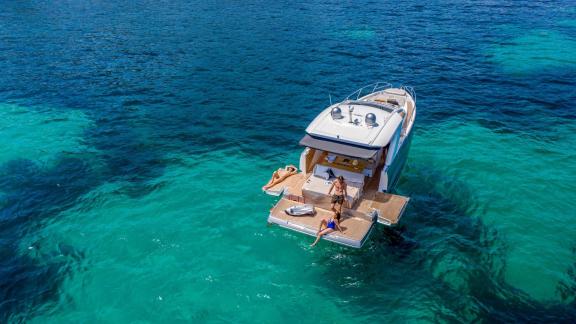 Gäste baden vom großzügigen Heck der Babel V bei einer Ibiza Tagesyachtcharter.