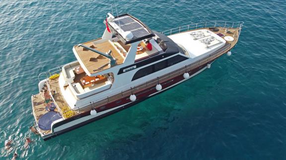 Menschen schwimmen neben der vor Anker liegenden Motoryacht Juliet vor der Küste von Bodrum.