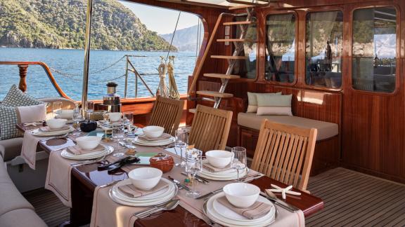 Bodrumda gulet kiralama seçeneği Kaftan arka güvertede şık yemek masası oturma alanı ve deniz manzarası ile keyifli anla