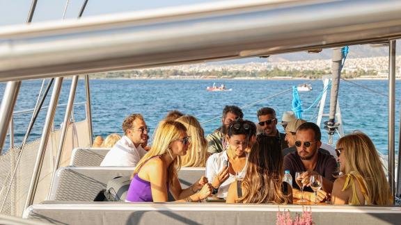 Group enjoying food and conversation during a catamaran day cruise along Greece’s coast.