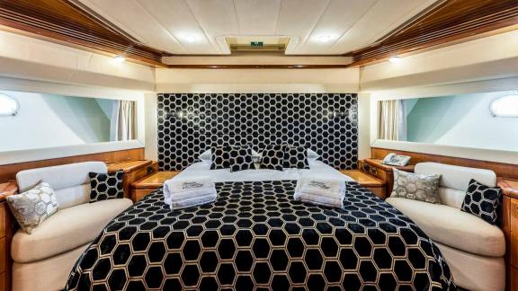 Stilvolles Hauptschlafzimmer mit luxuriöser Bettwäsche und gemütlichen Sitzbereichen auf der Motoryacht Katariina.