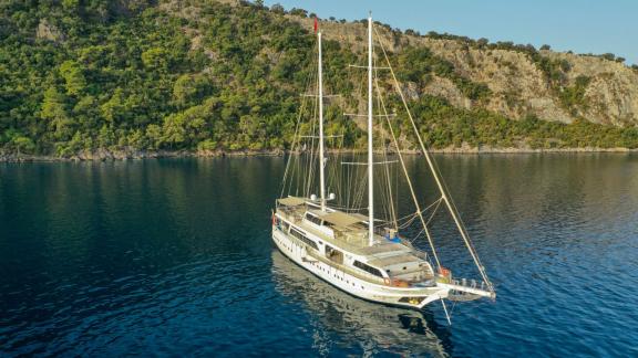 The magnificent Gulet Kayhan 11 anchored off a green coastline in Fethiye, Turkey.