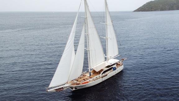 The gulet Kayhan 3 sails with full sails over the calm, wide sea.