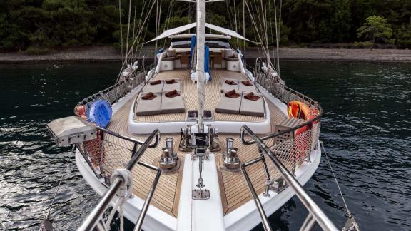 The deck of the Gulet Kayhan 3 offers comfortable sun loungers in front of a quiet coastline.