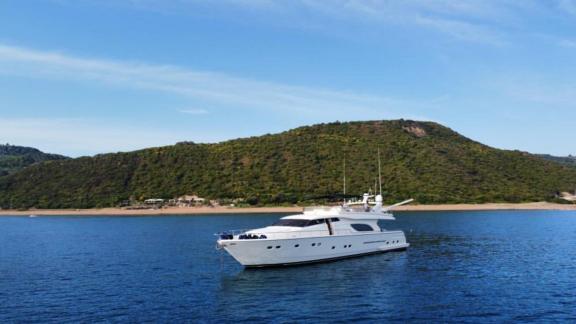 The Kentavros 2 yacht is anchored in a tranquil bay surrounded by greenery.