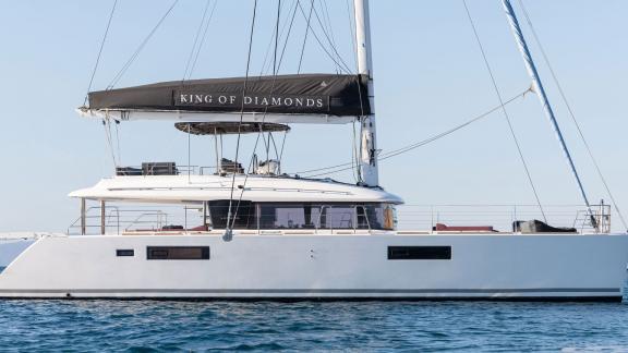 Side view of the King of Diamonds, a luxury Lagoon 560 catamaran, calmly resting on the water.