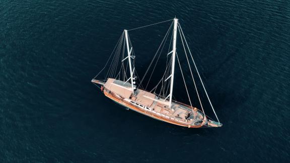 The gulet La Bella Vita in Bodrum, photographed from a bird's eye view, glides over the calm, deep blue water.