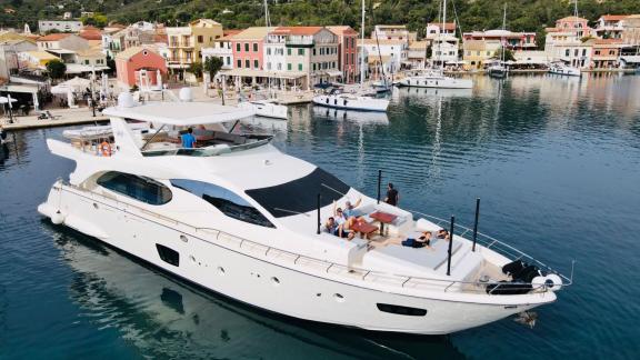 Elegant motor yacht with guests on board, docking in the picturesque harbor of Corfu.