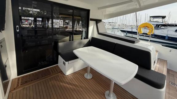 Among Athens bareboat catamaran charter options Bellatrix shows cockpit with seating and dining table.