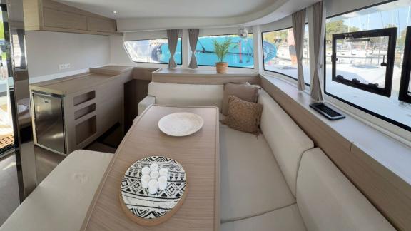 Bellatrix bareboat catamaran in Athens for 10 guests features lounge with seating and dining table.