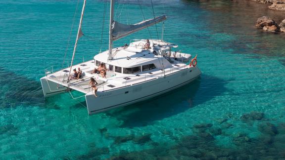 Katamaran Atlantis macht eine entspannte Pause im kristallklaren Wasser von Ibiza. Perfekte Wahl für Yachtcharter in Spa