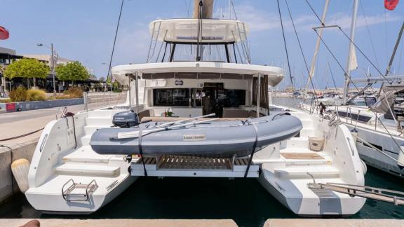 Among Rhodes catamaran charter options Escape 46 shows rear view with swim platform and tender boat.