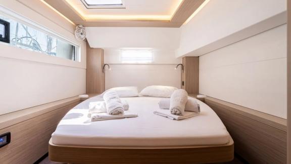 Among Rhodes catamaran charter options Escape 46 shows cabin with spacious bed and ambient ceiling lights.