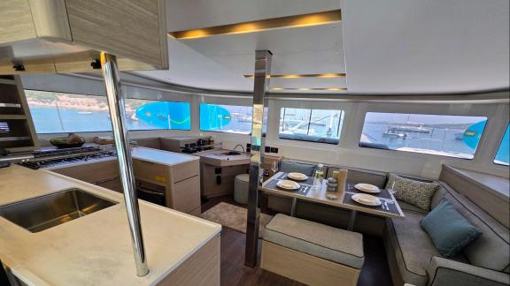 Inside Zalina, a bright salon with large windows, cozy seating, and a modern galley.