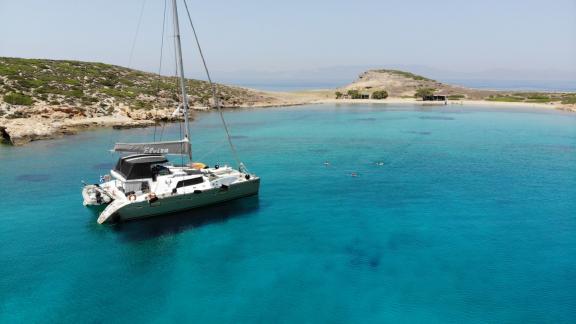 Der Katamaran Lagoon 500 Elvira ankert in einer abgelegenen, türkisfarbenen Bucht. Gäste schwimmen und genießen die Idyl