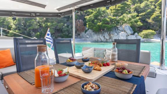 The aft deck of Aranel catamaran in Lefkada features a breakfast table with a scenic bay view.