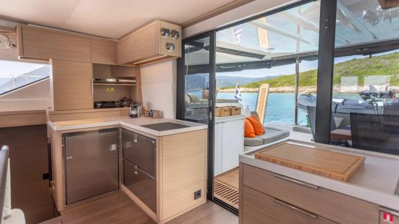 The galley area of Aranel catamaran in Lefkada features wide counters, cabinets and a sliding door to the aft deck.