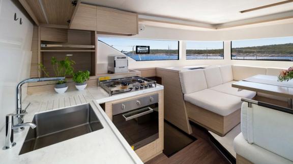 На фото — плита, духовка, рабочая зона и мягкий диван у панорамных окон.