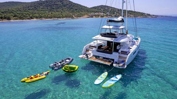 Der Katamaran liegt vor Athen und bietet Kajak, SUP, Tube und Beiboot im türkisfarbenen Wasser.