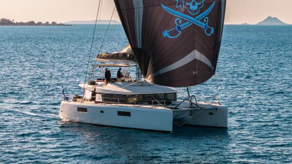 Largo Winch cruises off Mykonos with its eye catching sail, creating a unique catamaran charter experience.