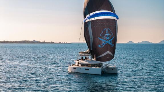 Largo Winch cruises off Mykonos with its distinctive sail, adding a unique touch to the catamaran charter experience.