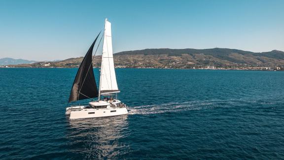 Largo Winch cruises along the coast of Mykonos, offering an ideal setting for an unforgettable catamaran charter.