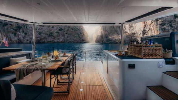 Set table and galley face a dramatic rocky passage in a calm secluded bay.