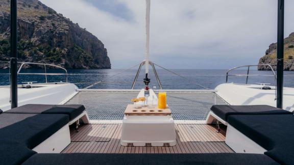 Drinks are served on the bow while anchored in a calm, cliff-lined cove.