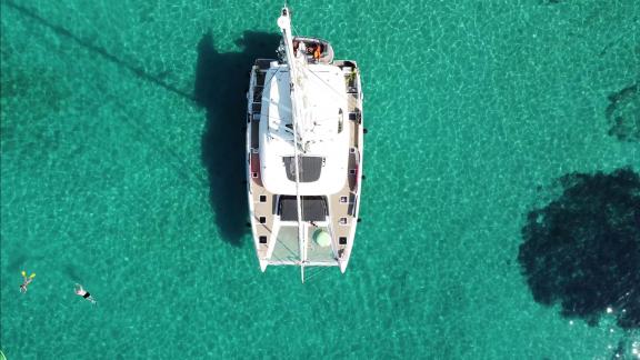 The Lagoon 55 Tri Wing is anchored in Kastela’s turquoise bay as guests swim in the clear sea below.