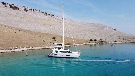 The Lagoon 55 Tri Wing sails smoothly in turquoise waters along Kastela’s calm and rocky shoreline.