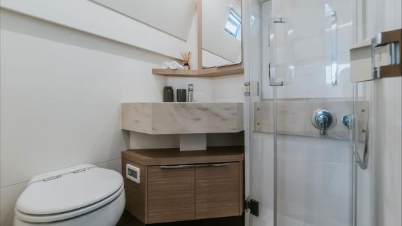 Among catamaran rental options Triwing Ossus bathroom with sink and storage shelves offers a clean and functional onboar