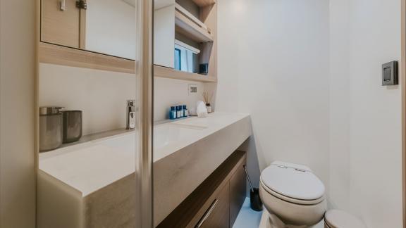 Among catamaran rental options Triwing Ossus bathroom with sink and toilet offers a clean and functional onboard space.