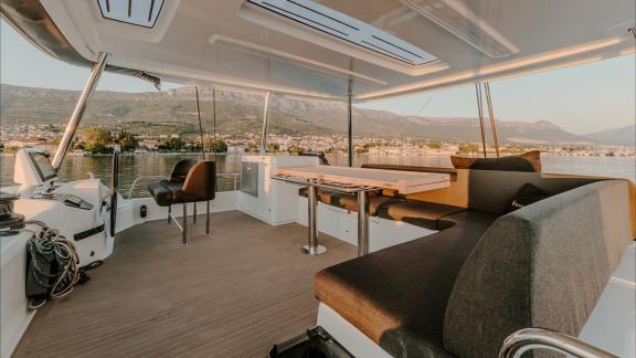 Among catamaran rental options in Kastela Triwing Ossus upper deck helm and seating area is seen anchored in calm sea.