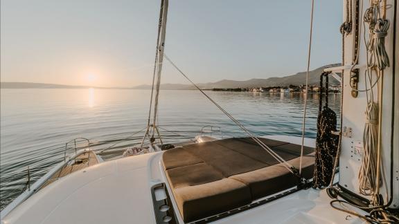 Among catamaran rental options in Kastela Triwing Ossus front deck seating area is seen anchored at sunset.