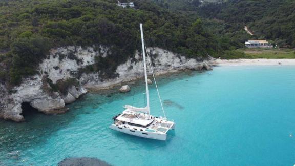 The white Grace Lagoon 620 catamaran is anchored in crystal clear turquoise waters.