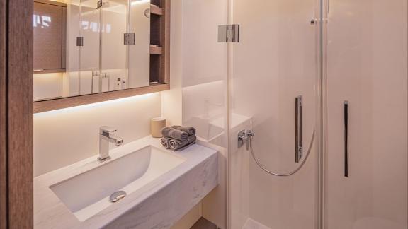 The bathroom of TriWing Endor features a sleek sink, glass shower, and elegant wood-accented styling.