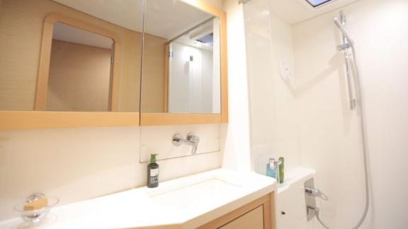 A modern and stylish bathroom on a Lagoon 560 catamaran in Göcek, featuring a large mirror, an elegant sink, and a comfo