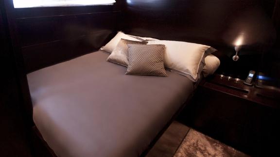 Among Cannes yacht charter options Cristal 1 motor yacht shows compact cabin with bed and bedside lighting.