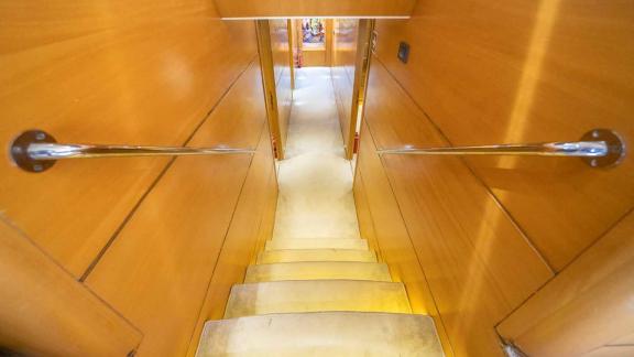 A staircase leads to the lower decks of a traditional Turkish gulet. The walls are clad in light-coloured wood and the s