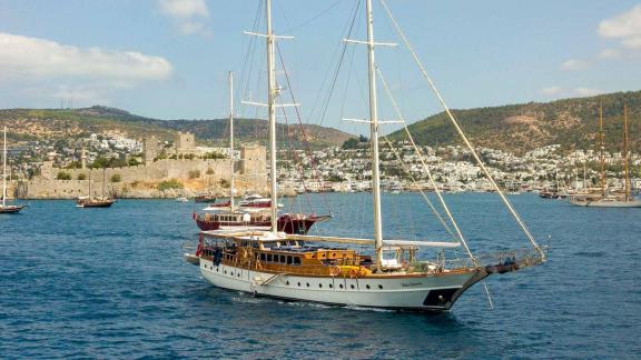 A traditional Turkish gulet with five cabins sails off the picturesque coast of Bodrum, Turkey, with the historic Bodrum