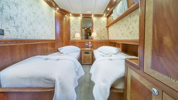 A comfortable twin cabin on board the Gulet Lotus with elegant wooden walls and stylish furnishings