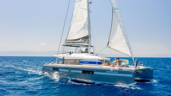 The luxurious Catamaran Lucky Clover glides gracefully through the open sea under a blue sky.