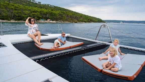 В Сплите семья отдыхает на подушках в носовой части катамарана Orange над сеткой.